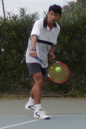 Executing the backhand with top-spin, hips uncoiling from a closed stance.